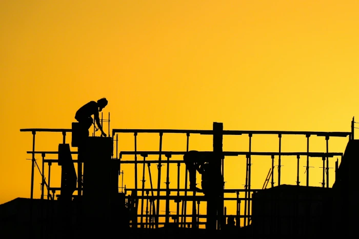 a silhouette of a construction worker on top of a building
